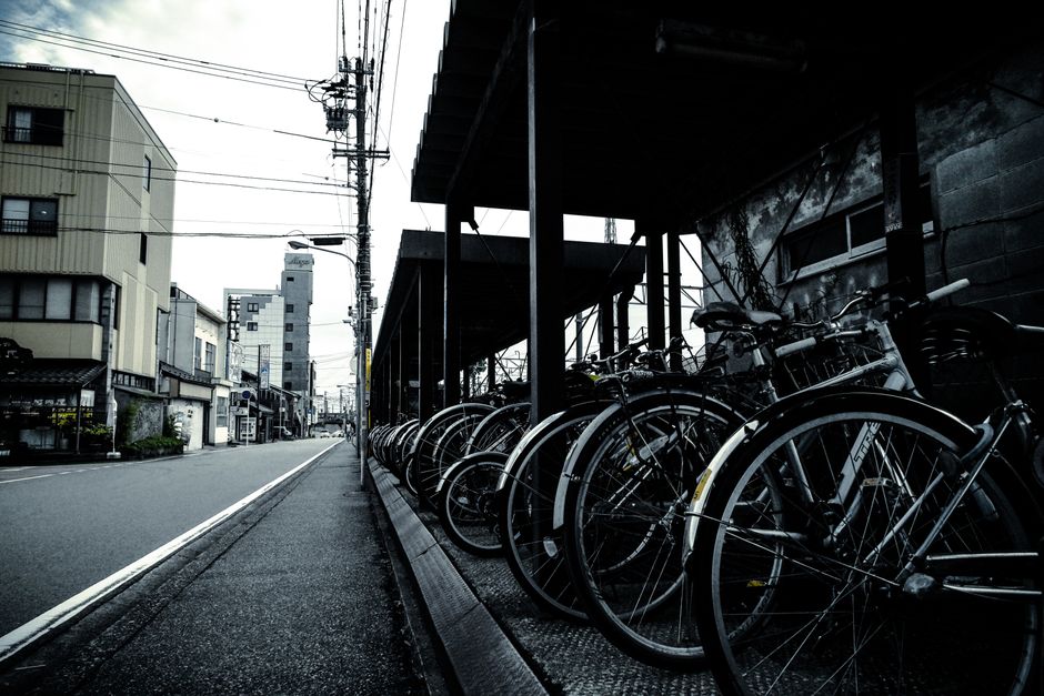 A row of parked bicycles along an urban street, showcasing city life and transportation.